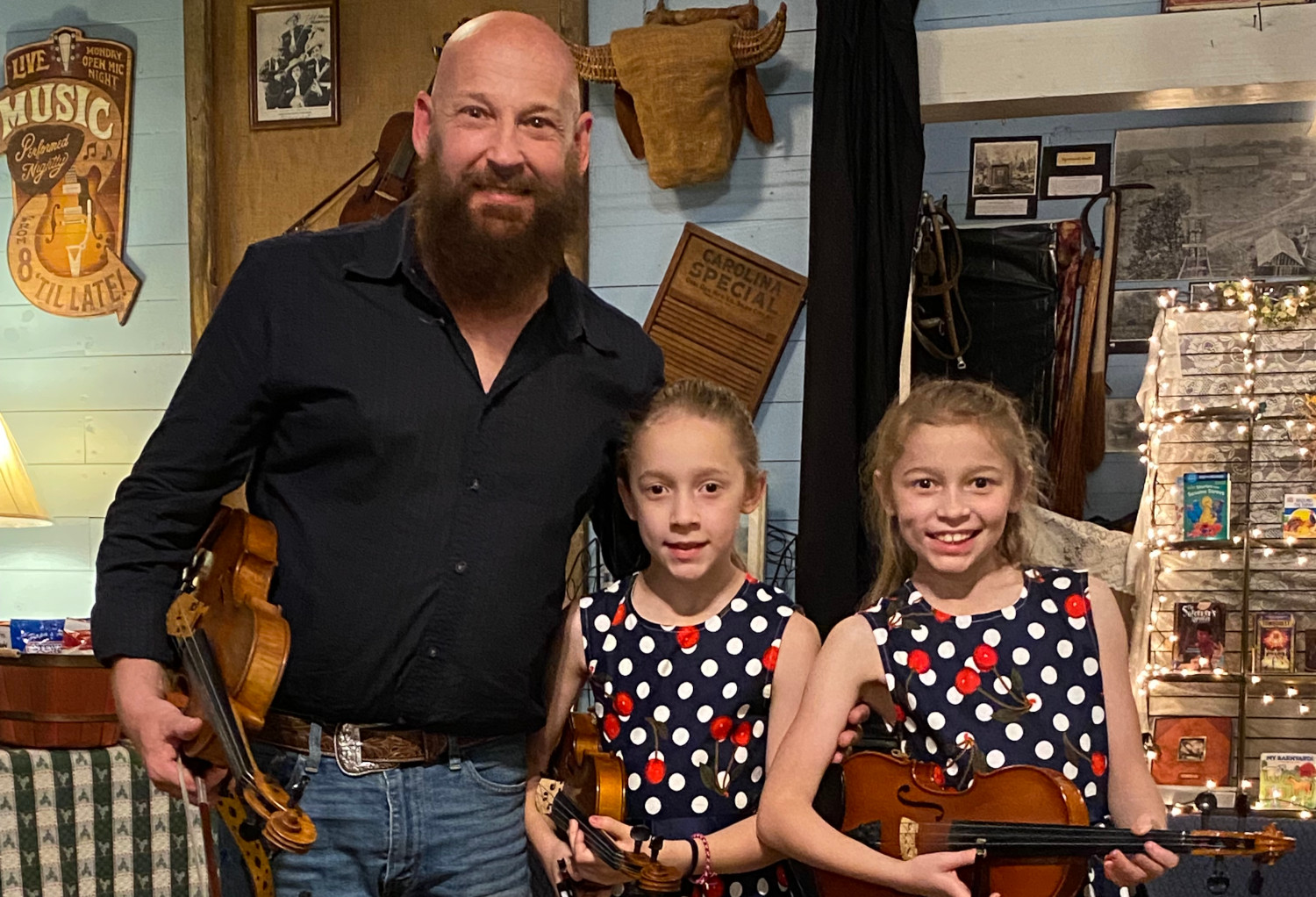 Fiddlin Fluds posed on porch positioned to play the fiddles